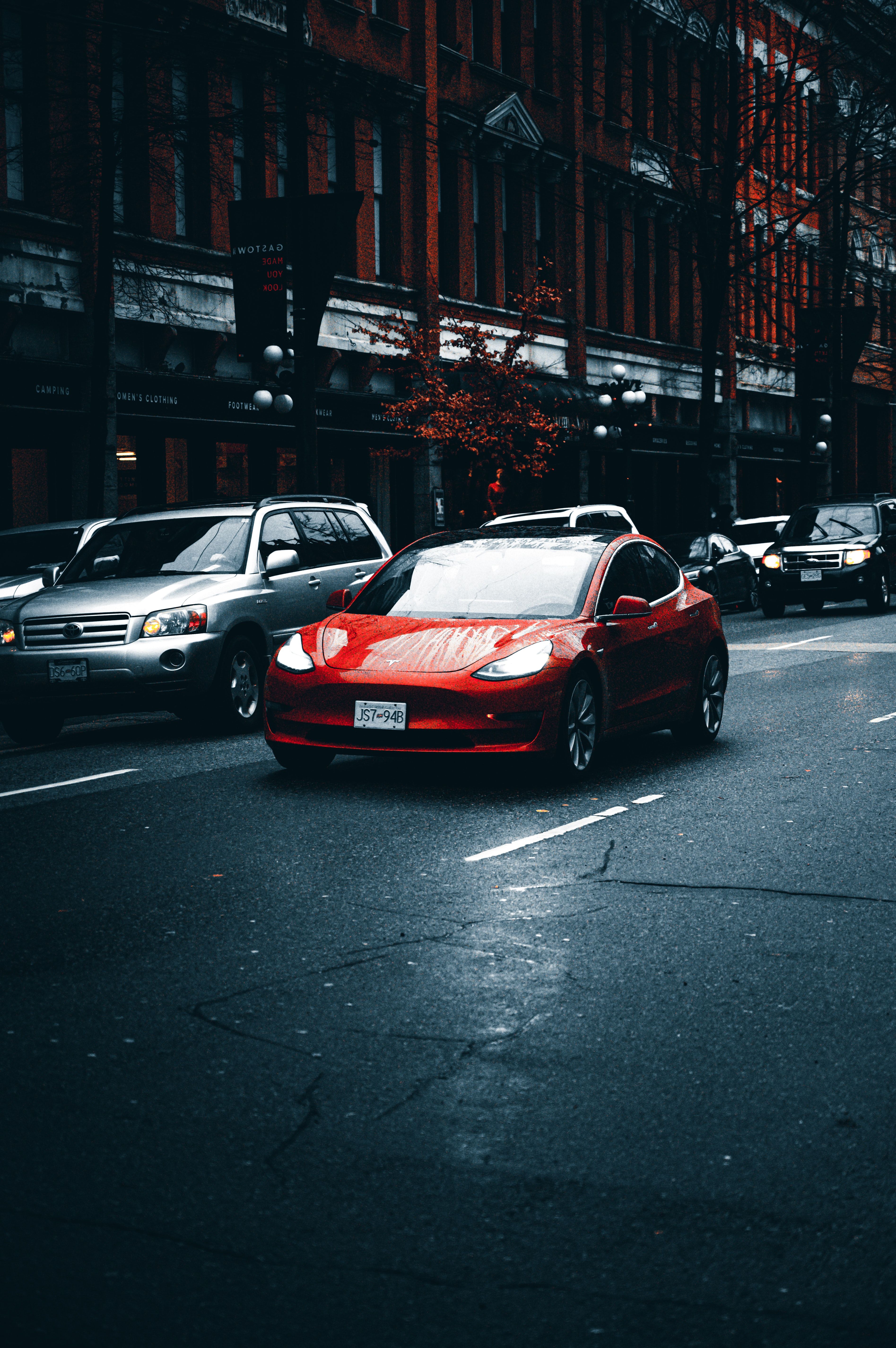 Tesla, Roter Elektroauto, Stadtstraße, Nasse Straße, Hochformat, QHD+, Handy-Hintergrund
