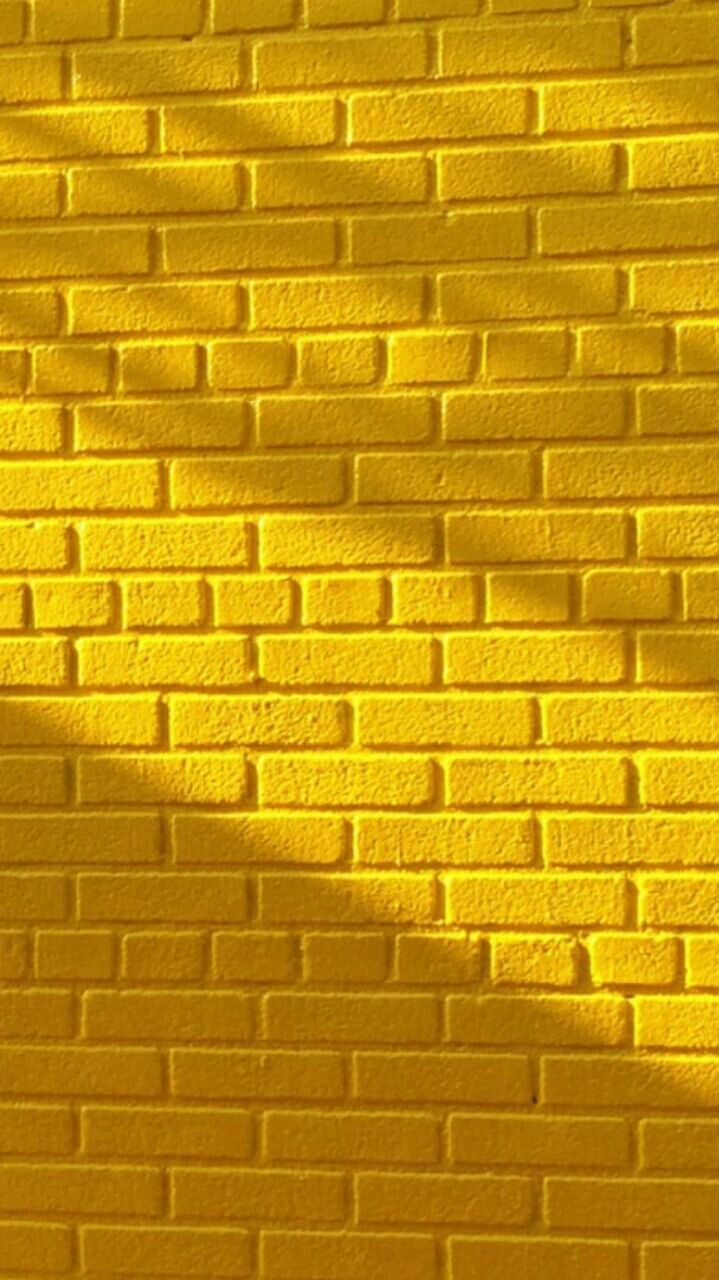 Gelbe Ziegelwand, Sonnenlicht, Schatten, Textur, Hochformat, Hintergrundbild fürs Smartphone