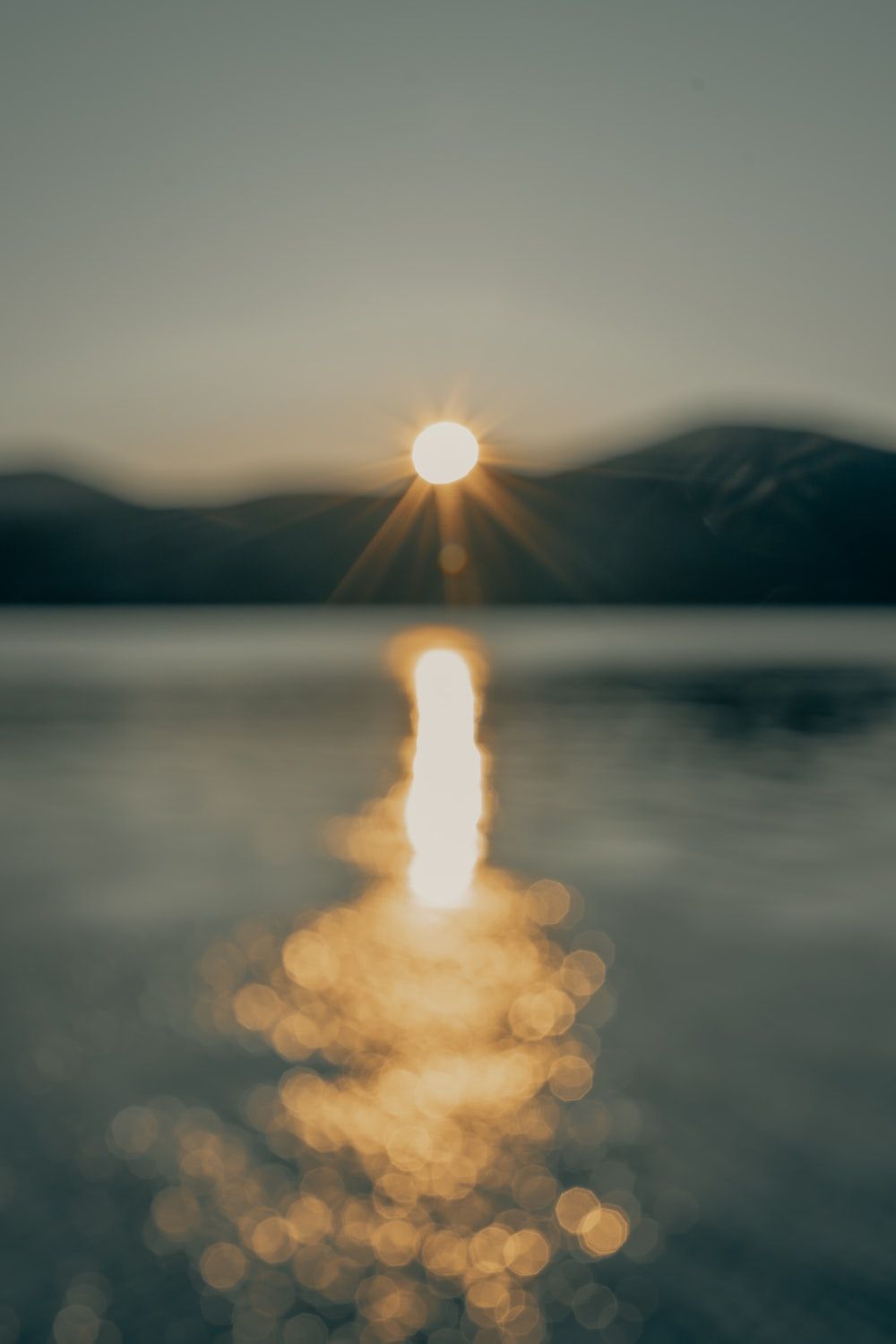 See, Sonnenuntergang, Sonnenstern, Spiegelung, Berge, Hintergrundbild für iPhone und Android